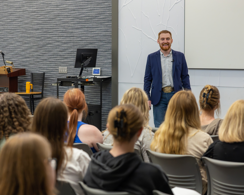 Speaker presenting to a seated audience in a campus event space.